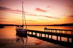 Zdjęcie przedstawia zacumowany jacht żaglowy na jeziorze Necko w trakcie zachodu słońca, fot. J. Koniecko
