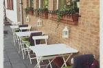 Zdjęcie przedstawia białe stoliki, stojące wzdłuż budynku restauracji  Szuflada Cafe&Bar