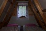 Zdjęcie przedstawia wnętrze domku letnistkowego, widoczne dwa posłania: materac, na którym leży pościel i poduszka.